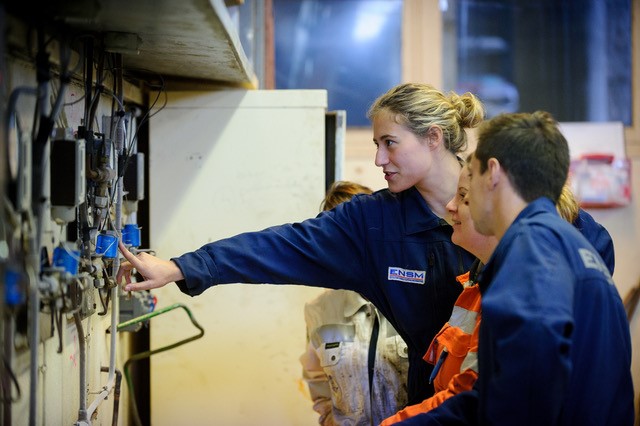 A young women showing marine engineering students electrical equipments