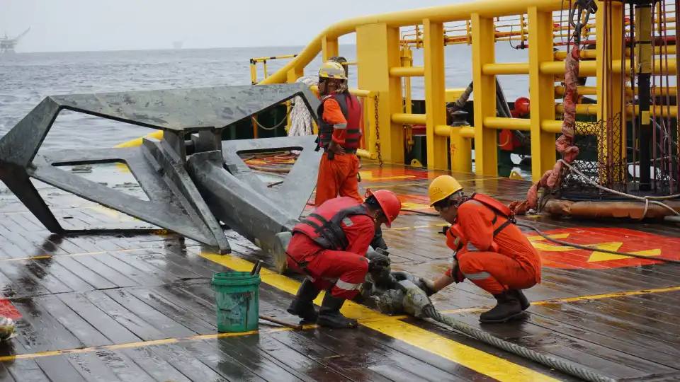 Seafarers with PPE operating an anchor