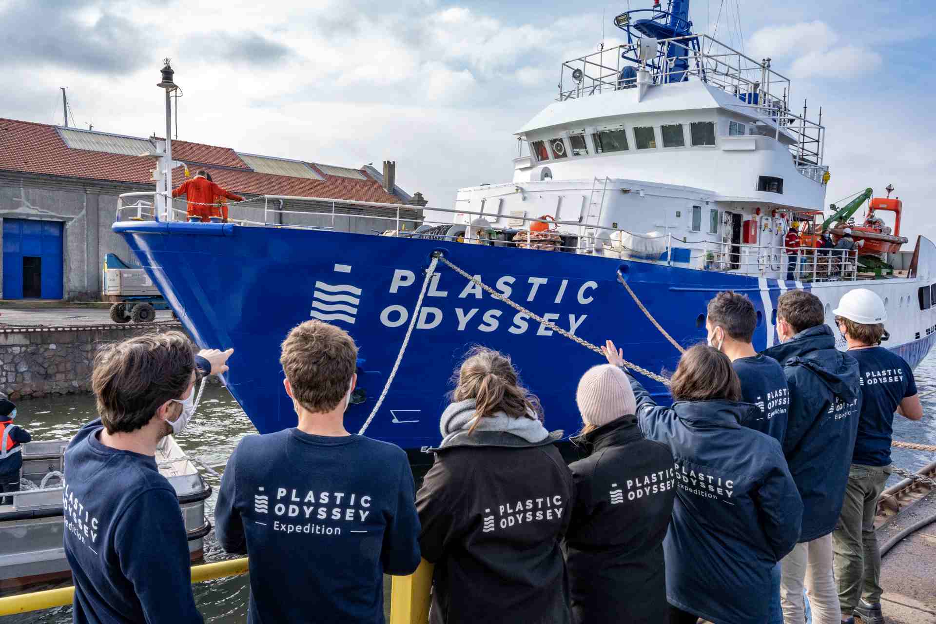 Plastic Odyssey boat launching in Dunkerque, some association members are standing on the dock, looking at the Plastic Odyssey ship.