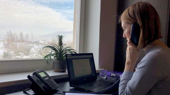 Helpline Officer at ISWAN sitting at her desk and talking over the phone